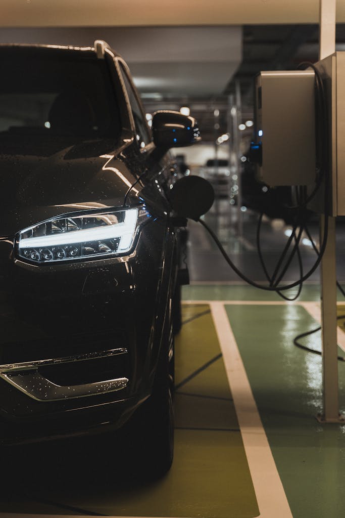 Luxury electric car charging at a station in Curitiba parking garage.