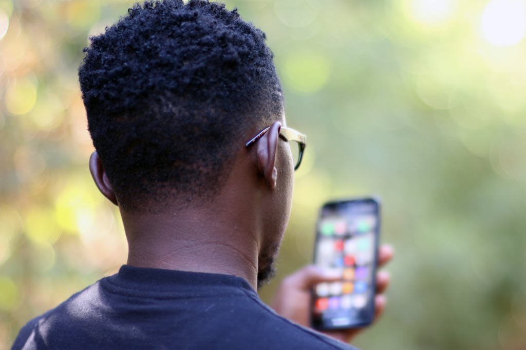 Rear view of a young black man using a smartphone outdoors in Kenya.